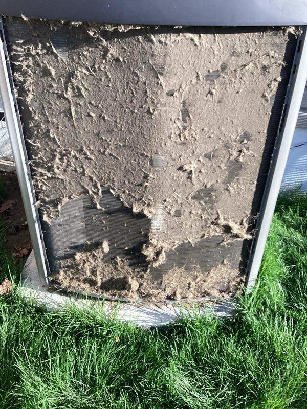 Responded to a no-cool complaint on a 2-year-old Lennox central air conditioning system. Upon inspection, discovered the outdoor unit's filter and front panel were heavily contaminated with dirt, dust, and debris buildup, severely restricting airflow to the condenser coil. Removed and cleaned the excessively soiled filter, which was clogged with gray-tan dust accumulation that had significantly impaired system performance and cooling capacity. The restricted airflow condition was causing inadequate heat rejection at the condenser, resulting in reduced cooling output to the living space. System restored to proper operation following cleaning.