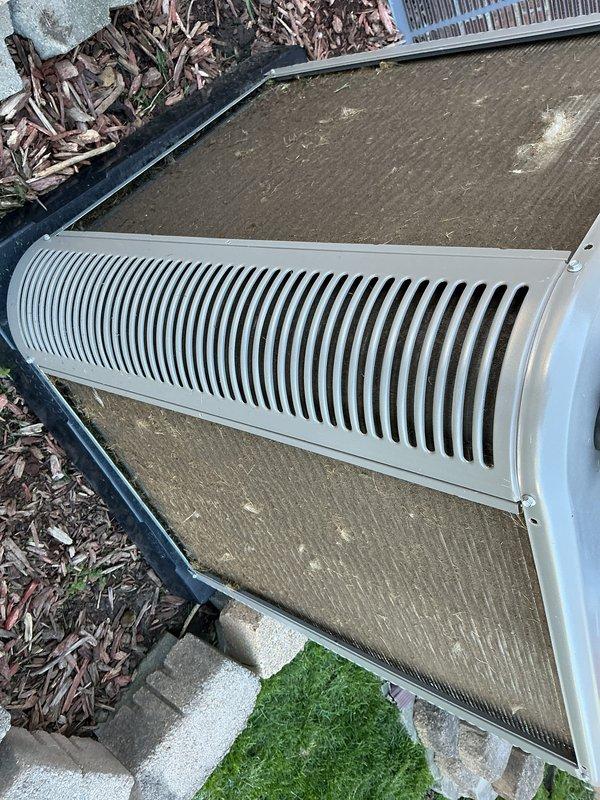 Completed scheduled Air Care Maintenance on residential HVAC system. Performed comprehensive inspection of outdoor condensing unit, noting accumulated debris and environmental buildup on top panel and filter surfaces. Documented unit condition showing operational mesh grilles and ventilation components in serviceable condition, with equipment properly positioned on concrete pad foundation with adequate clearance for airflow.