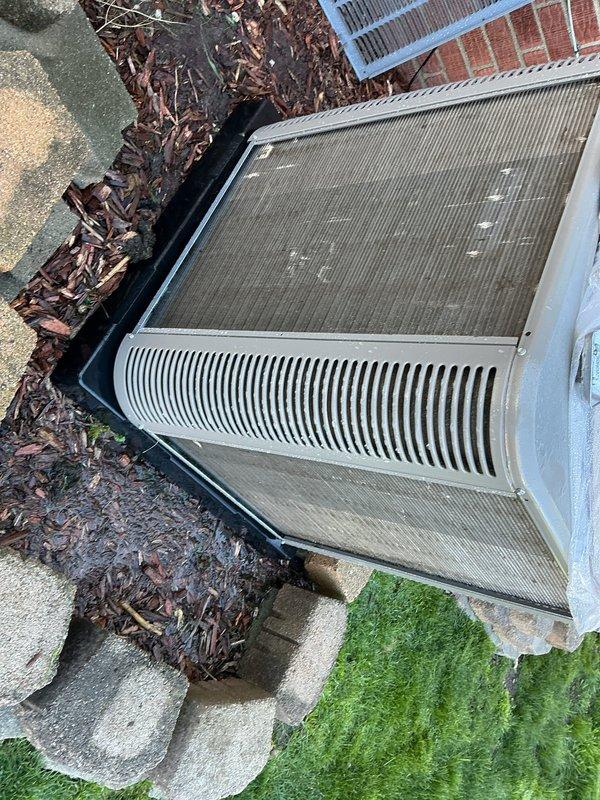 Completed scheduled Air Care Maintenance on residential HVAC system. Performed comprehensive inspection of outdoor condensing unit, noting accumulated debris and environmental buildup on top panel and filter surfaces. Documented unit condition showing operational mesh grilles and ventilation components in serviceable condition, with equipment properly positioned on concrete pad foundation with adequate clearance for airflow.