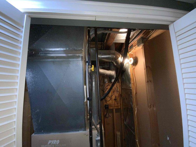 Provided comprehensive replacement estimate for 25-year-old residential HVAC system located in basement utility area. Assessed existing furnace, air conditioning unit, and hot water heater for complete system replacement, with current furnace being the only operational component. Documented existing equipment configuration including dark gray heating/cooling unit, cylindrical water heater with expansion tank and copper piping, and associated ductwork within confined mechanical room space accessed through louvered bifold doors.