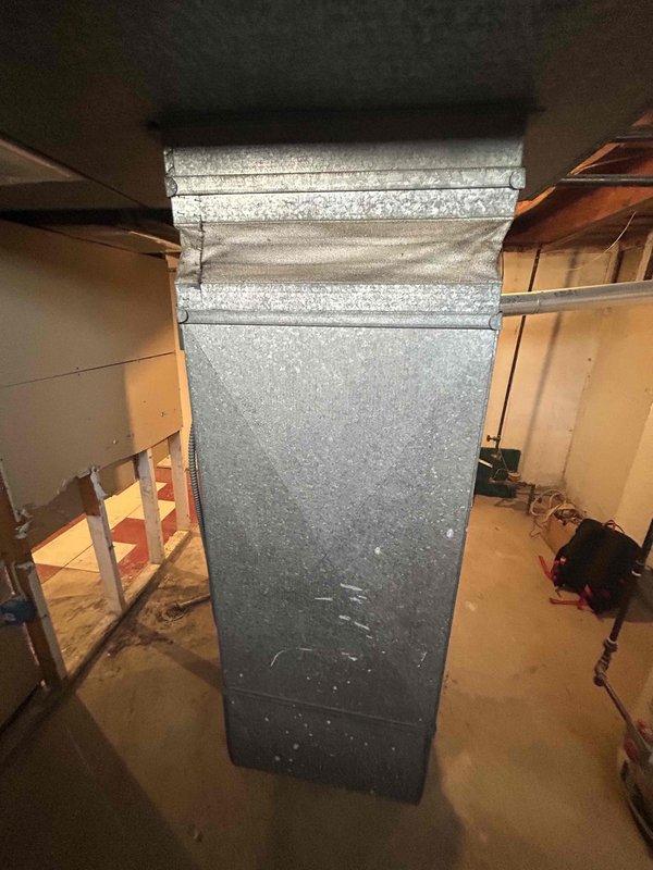 Completed site visit to assess 16-year-old HVAC system for full replacement estimate. Inspected existing ductwork in basement area, noting corrugated metal supply ducts with dust accumulation and aged elbow connections showing deterioration at wall penetration points. Documented current system configuration with photos of ductwork components and connections to facilitate accurate replacement proposal for customer requesting immediate system replacement.
