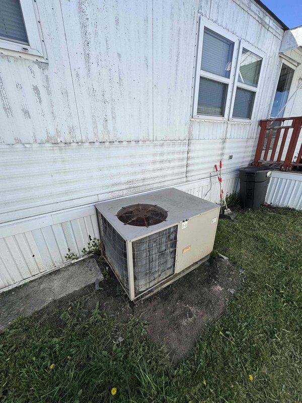 Completed full system estimate for residential HVAC replacement involving a 1998 furnace and failed air conditioning unit. System exhibited multiple failures including AC blowing hot air followed by complete heating failure approximately one week later. Assessed unusual dual-thermostat configuration connected to single furnace unit, with previous owners indicating separate thermostats for heating and cooling despite both units having full HVAC control capability. Documented existing equipment located in interior utility closet alcove and exterior condensing unit positioned on concrete pad against mobile home exterior. Measured installation space dimensions and photographed current system configuration including furnace with flexible ductwork connection and weathered outdoor AC unit. Provided comprehensive replacement options for complete heating and cooling system due to age of equipment and extent of failures making repair economically unfeasible.