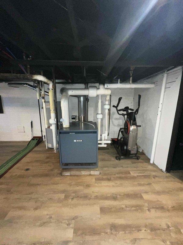 Conducted on-site evaluation for new residential air conditioning system installation in a finished basement space currently equipped with existing heating equipment. Assessed the mechanical room layout, existing ductwork infrastructure, and available space for AC equipment placement. Documented current HVAC configuration including furnace location, PVC venting system, and overhead duct distribution network. Evaluated electrical service accessibility and determined optimal placement for new condensing unit and air handler to integrate with existing heating system. Photographed existing mechanical equipment, ceiling-mounted ductwork, and basement layout to develop comprehensive installation proposal for complete cooling system addition.