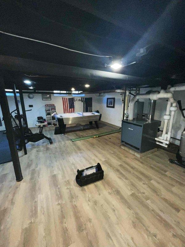 Conducted on-site evaluation for new residential air conditioning system installation in a finished basement space currently equipped with existing heating equipment. Assessed the mechanical room layout, existing ductwork infrastructure, and available space for AC equipment placement. Documented current HVAC configuration including furnace location, PVC venting system, and overhead duct distribution network. Evaluated electrical service accessibility and determined optimal placement for new condensing unit and air handler to integrate with existing heating system. Photographed existing mechanical equipment, ceiling-mounted ductwork, and basement layout to develop comprehensive installation proposal for complete cooling system addition.