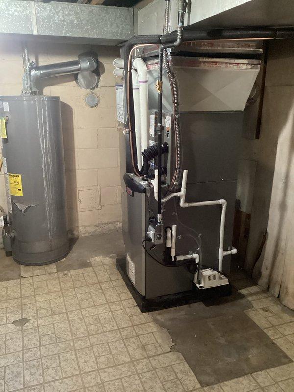 Completed full HVAC system installation including 70,000 BTU furnace with humidifier and liner, 2-ton air conditioning unit with rear discharge configuration, and new dedicated electrical circuit. All mechanical and electrical permits obtained prior to installation. System professionally installed in basement utility area with proper venting, PVC condensate drainage, copper refrigerant lines, and galvanized ductwork connections per code requirements.