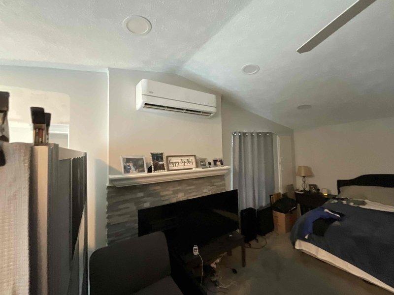 Performed on-site evaluation of 9-10 year old ductless mini-split system in bedroom application. Previous service provider determined repair costs exceeded value of unit and recommended full system replacement. Assessed existing indoor wall-mounted evaporator unit positioned above decorative fireplace and exterior condensing unit with associated electrical service components including meter, disconnect boxes, and conduit routing. Documented current system configuration through photographic documentation of both interior air handler installation and exterior condenser placement with electrical connections. Provided replacement estimate for new ductless mini-split system to restore climate control functionality.