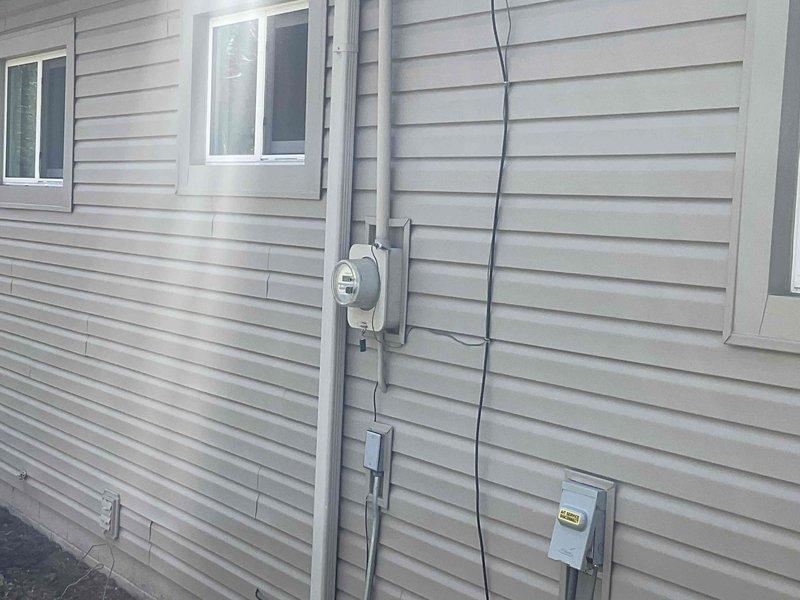 Performed on-site evaluation of 9-10 year old ductless mini-split system in bedroom application. Previous service provider determined repair costs exceeded value of unit and recommended full system replacement. Assessed existing indoor wall-mounted evaporator unit positioned above decorative fireplace and exterior condensing unit with associated electrical service components including meter, disconnect boxes, and conduit routing. Documented current system configuration through photographic documentation of both interior air handler installation and exterior condenser placement with electrical connections. Provided replacement estimate for new ductless mini-split system to restore climate control functionality.