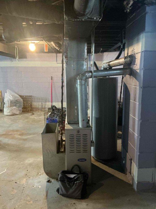 Provided comprehensive estimate for replacement of 15-year-old non-operational natural gas furnace located in basement utility area. Assessed existing Carrier furnace unit, evaluated ductwork connections, and reviewed installation requirements for new equipment replacement. Documented current system configuration including water heater placement and available workspace for equipment changeout.