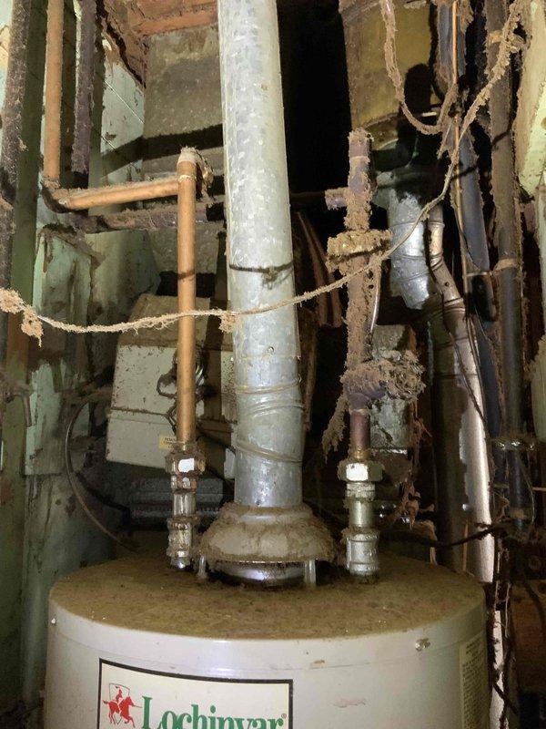 Provided estimate for replacement of leaking 40-gallon natural draft water heater. Inspected existing Lochinvar unit installed in exposed wall cavity with deteriorated surrounding structure and aging plumbing connections including galvanized and copper piping. Assessed installation location, venting configuration, and structural conditions to prepare quote for standard tank-style water heater replacement.
