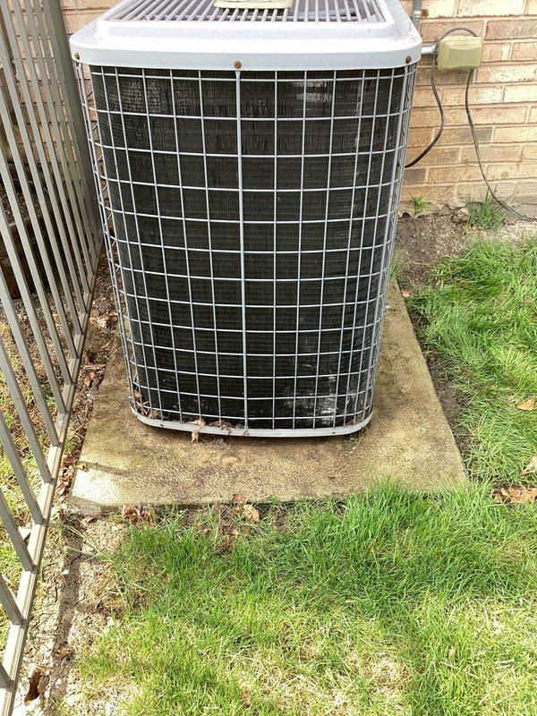 Completed scheduled maintenance on outdoor air conditioning condenser unit. Performed comprehensive inspection of cylindrical condenser system with protective wire guard cage, verified unit operational status, and documented equipment condition through photographic records. All components found functioning within normal parameters with unit showing typical age-related wear on exterior protective cage and minor base discoloration consistent with outdoor exposure.