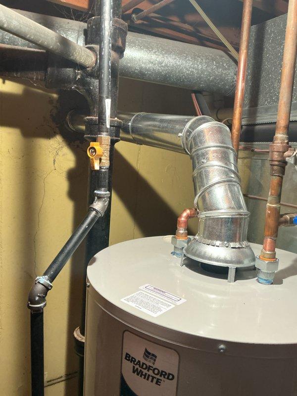 Installed a 40-gallon Bradford White tanked water heater in residential utility area. Connected all water supply lines using copper piping with appropriate fittings, installed exhaust vent assembly with galvanized metal flue pipe extending through ceiling, and reconnected gas line with flexible black connector. Verified all connections for proper operation and code compliance per mechanical permit requirements.