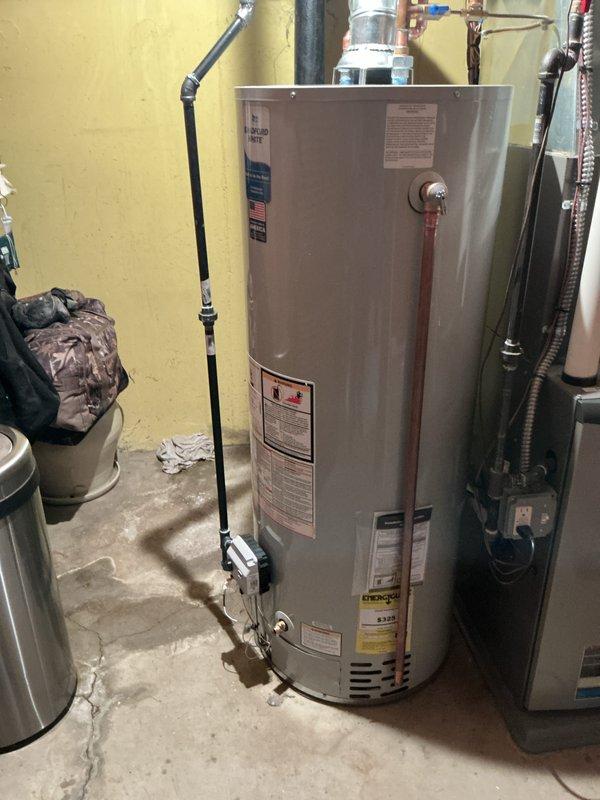Installed a 40-gallon Bradford White tanked water heater in residential utility area. Connected all water supply lines using copper piping with appropriate fittings, installed exhaust vent assembly with galvanized metal flue pipe extending through ceiling, and reconnected gas line with flexible black connector. Verified all connections for proper operation and code compliance per mechanical permit requirements.