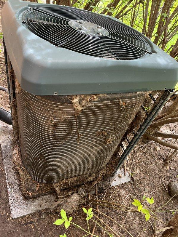 Completed annual cooling maintenance on residential air conditioning system. Inspected outdoor condenser unit, which showed significant debris accumulation in fins and coils from surrounding vegetation. Cleaned condenser coils and exterior surfaces, removed leaves, twigs, and organic matter from fin assembly to restore proper airflow and heat transfer efficiency. Verified unit operation and documented equipment condition with photos for customer records.