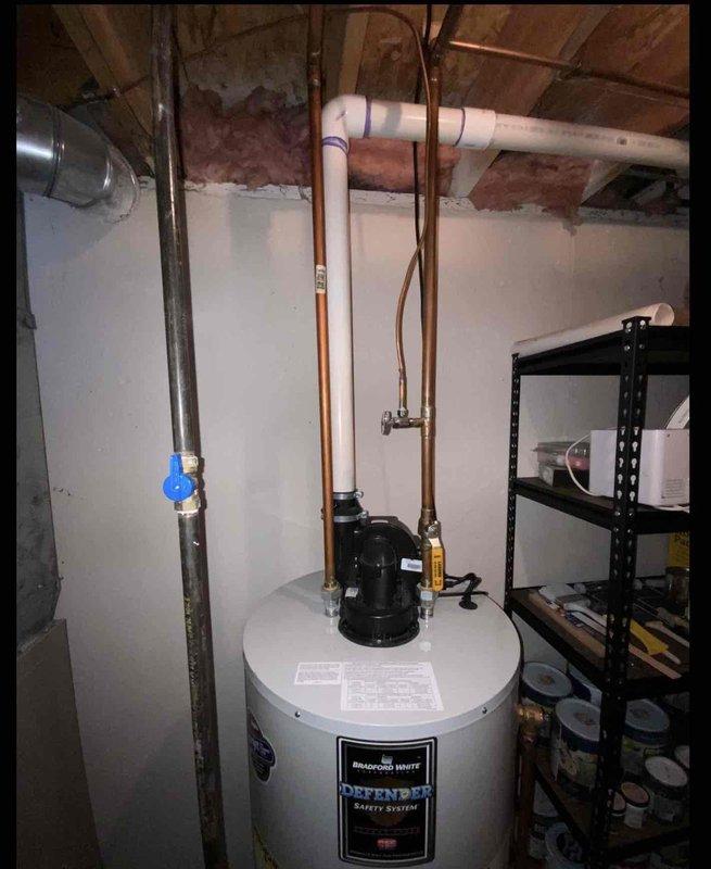 Performed comprehensive water heater assessment in basement utility area for existing Bradford White Defender Safety System unit that was operational but experiencing performance issues. Evaluated current installation configuration including copper supply piping, pressure relief valve, expansion tank mounted on top of unit, shut-off valves, and venting system to determine replacement specifications. Documented existing natural draft or power vent setup, photographed current equipment layout including proximity to HVAC system and available clearances, and provided estimate for new water heater installation to restore optimal hot water delivery and system efficiency.