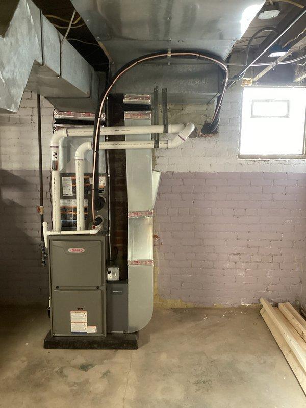 Successfully completed full HVAC system installation including new furnace and air conditioning unit in basement mechanical room. Installed ML196UH070XE36BK-01 furnace on base platform with proper venting and ductwork connections, including curved metal supply duct routed to ceiling distribution system. Connected all necessary gas lines, condensate drainage via PVC piping, electrical connections, and verified proper clearances from combustible materials. System tested and operational, with all permits requested for final inspection.