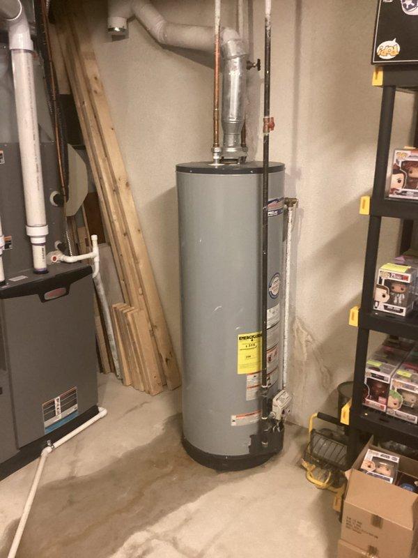 Responded to no hot water complaint affecting entire house. Upon inspection, found existing tanked water heater in basement utility area with active leak at base of unit, resulting in moisture staining on concrete floor and complete loss of hot water supply. Assessed water heater condition, verified leak source, and documented equipment specifications and surrounding mechanical systems. Photographed affected unit showing manufacturer labels, Energy Guide sticker, and evidence of water damage to floor surface. Evaluated venting system, plumbing connections, and electrical components. Provided customer with findings and replacement recommendations due to tank failure.