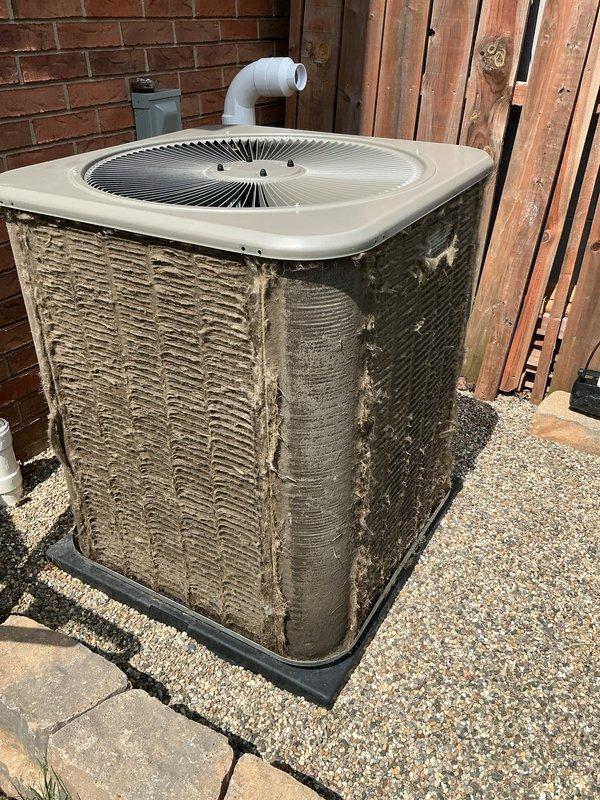 # HVAC Maintenance - ACM Completed

Performed comprehensive air conditioning maintenance on outdoor condenser unit. Upon arrival, discovered extremely heavy accumulation of lint, dust, and fibrous debris coating the exterior condenser coils and side panels. The buildup was significantly restricting airflow and indicated extended period of maintenance neglect, with thick matted layers covering nearly all exposed coil surfaces.

Thoroughly cleaned condenser coils using appropriate methods to remove the dense accumulation of debris from all accessible surfaces. Cleared obstructions from the unit's metal fins and exterior panels to restore proper airflow capacity. Inspected unit mounting, concrete pad, and surrounding gravel base for stability and drainage. Verified PVC condensate line routing and condition. System operational following cleaning and maintenance procedures.