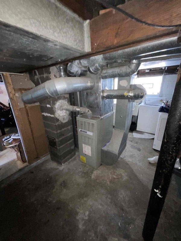 Provided estimate for complete HVAC system replacement including natural gas furnace and air conditioning unit for 30-year-old equipment located in basement mechanical room. Current air conditioning system non-operational while furnace remains functional. Assessed existing ductwork configuration, electrical disconnects, and outdoor condenser placement on decorative rock bed adjacent to home exterior with vinyl siding.