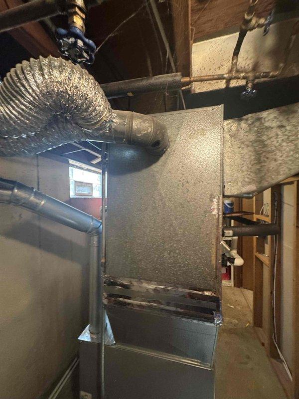 Conducted comprehensive full system evaluation for 16-year-old HVAC equipment located in basement with distribution through attic space. Assessed existing furnace showing signs of condensation on exterior surfaces, inspected flexible ductwork installation throughout attic crawl space including insulated silver flex ducts wrapped around structural supports, and evaluated overall system condition including copper refrigerant lines and air distribution components. Provided complete replacement system estimate with recommendations for immediate installation based on equipment age and current operating condition.