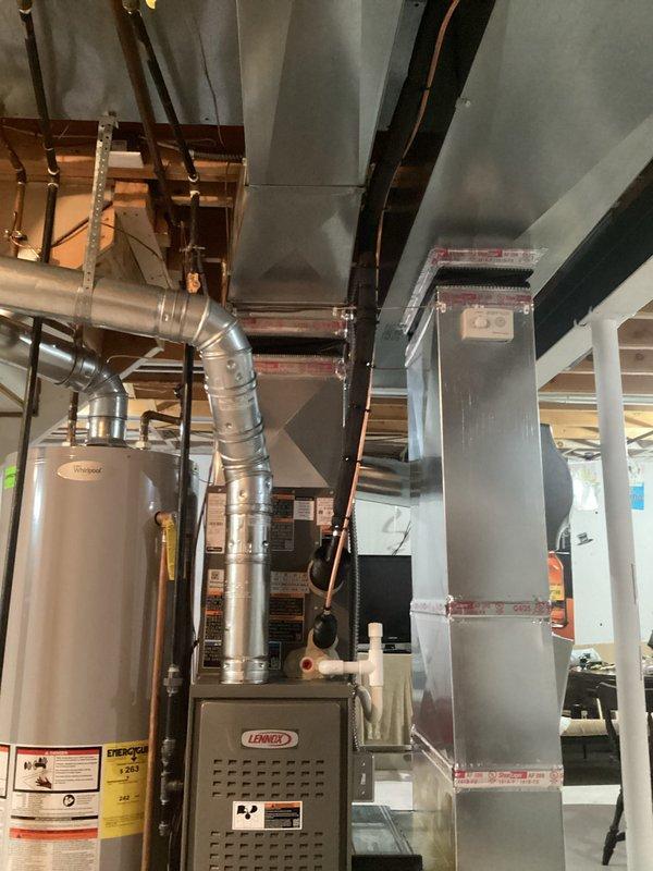 Completed full HVAC system installation in basement mechanical room including new Lennox 70,000 BTU furnace with humidifier and 2-ton air conditioning unit with rear discharge configuration. Installed all necessary metallic ductwork connections with proper sealing at joints and reconnected existing utility infrastructure to new equipment. All mechanical permits obtained prior to installation, system tested and operational upon completion.