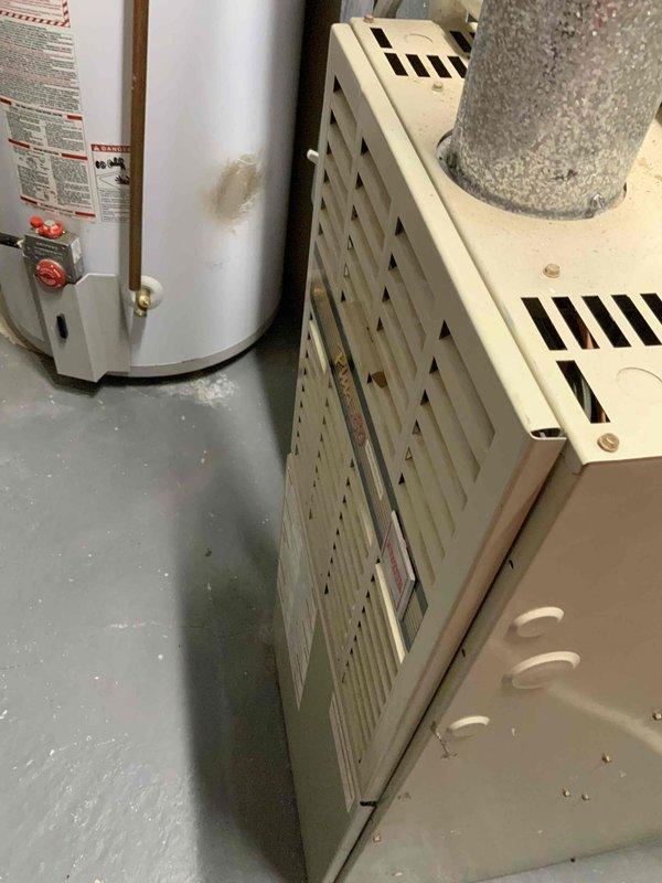 Conducted comprehensive assessment of existing HVAC system for full replacement estimate. Evaluated 31-year-old original furnace and air conditioning unit from 1995, both at end of serviceable life. Inspected furnace with perforated metal grille panel and diagonal ventilation pattern in basement utility area. Examined ductwork showing significant dust accumulation and surface discoloration indicating age-related deterioration. Assessed air handler components and ventilation infrastructure. Documented existing equipment configuration, duct connections, and overall system condition through photographic documentation. Provided detailed estimate for complete furnace and air conditioner replacement to restore efficient climate control operation.