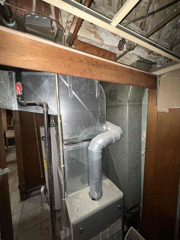 Provided estimate for complete HVAC system replacement in basement location, including new furnace and cooling unit for small to mid-sized residential space (0-1200 sq.ft.). Assessed existing utility room with water heater and determined electrical panel upgrade required to support new equipment installation. Documented current basement mechanical room configuration with exposed framing, existing ductwork, and available installation space for proposed system components.