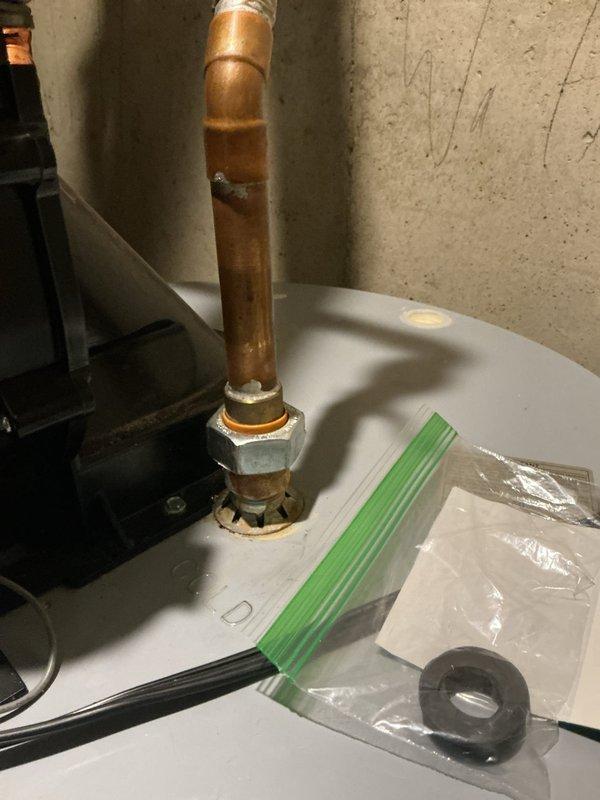 Replaced both rubber washers on the hot water tank to address leaking at pipe penetrations through the drain pan. Removed old deteriorated washers, cleaned the mounting surfaces, and installed new rubber grommets to ensure proper seal and prevent water damage.