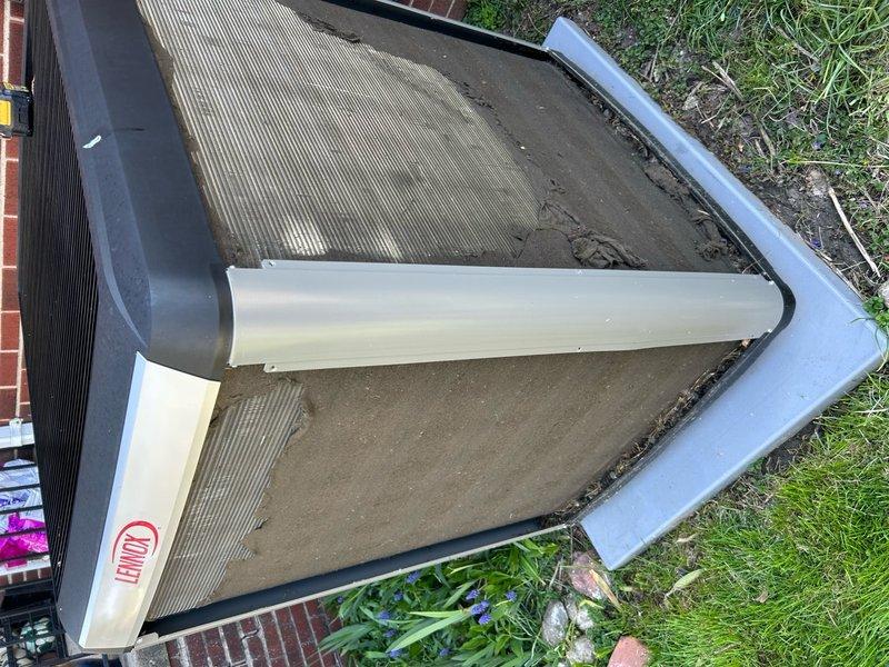 Completed annual preventative maintenance on outdoor condensing unit. Inspected V-shaped condenser coils which showed significant accumulation of dirt, dust, and debris on exterior surfaces and between fins. Documented unit condition with photographs showing heavy soiling on top panel and heat exchanger components. Unit operational at time of service with no immediate mechanical concerns noted, though coil cleaning recommended to maintain optimal heat transfer efficiency and system performance.