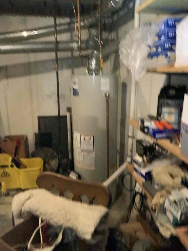 Conducted comprehensive assessment of 24-year-old residential HVAC system for replacement estimate. Evaluated existing furnace located in basement utility area with current water heater and ductwork configuration, and inspected outdoor air conditioning condenser unit positioned on concrete pad against exterior brick wall with glass block basement windows. Documented equipment conditions, spatial constraints, and existing infrastructure including copper piping, electrical panel access, and metal ductwork routing to provide accurate replacement system recommendations and installation requirements.