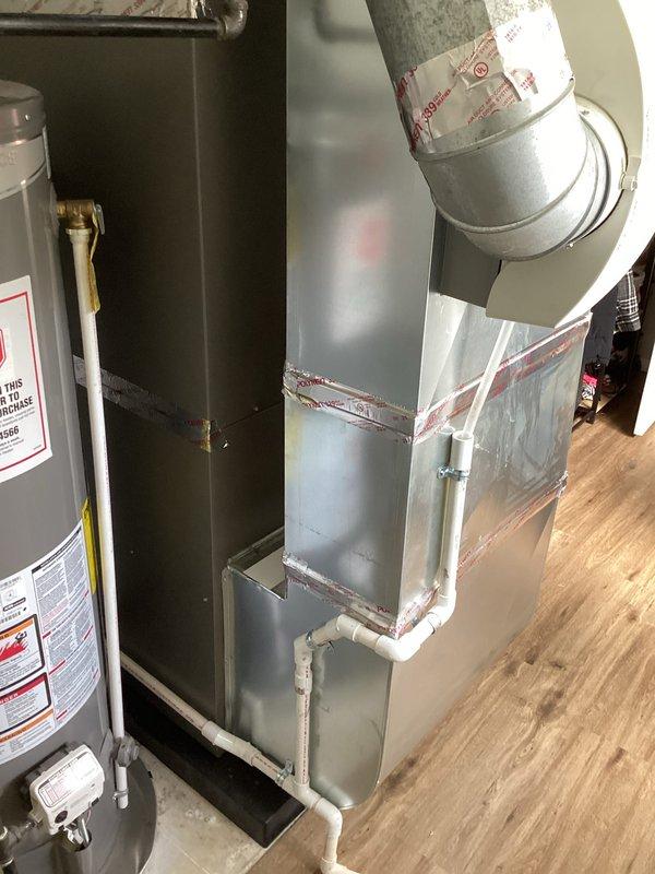 Completed full HVAC system installation including a 90,000 BTU furnace and 3-ton air conditioning unit with rear discharge configuration. Installed outdoor condensing unit on gravel pad with proper drainage, ran electrical conduit and refrigerant lines to exterior wall, and positioned furnace in utility area with water heater. Connected all ductwork, installed condensate drain lines using white PVC piping, secured vertical galvanized duct runs with metal strapping, and completed all electrical reconnections. Verified proper system operation, airflow, and drainage functionality upon startup.