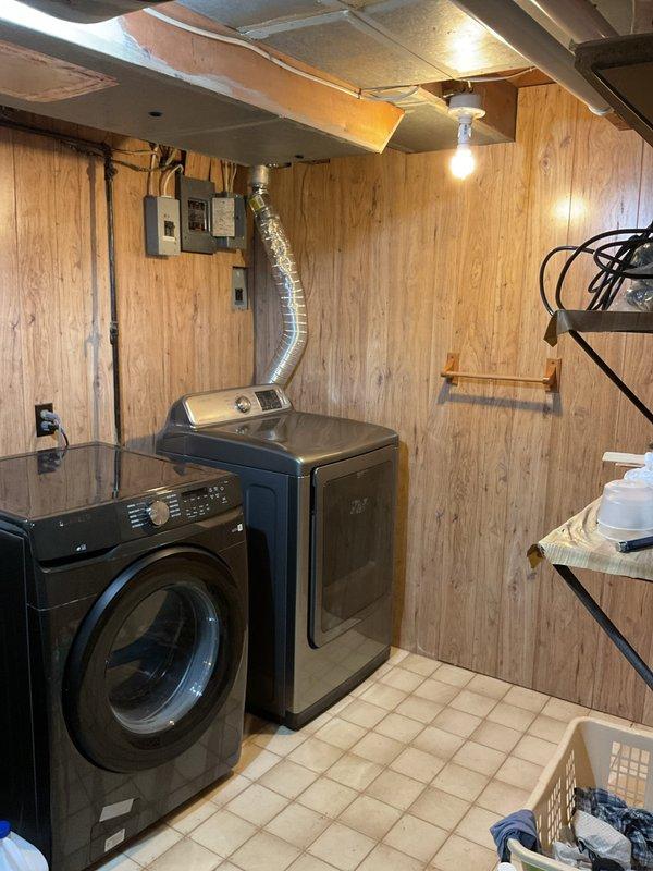 Conducted comprehensive electrical panel upgrade estimate in basement laundry room area. Assessed existing electrical panel box mounted on wall adjacent to laundry appliances, documented current panel configuration, examined overhead wiring runs along exposed ceiling joists, and evaluated junction box connections in utility space. Photographed electrical infrastructure including panel location, surrounding clearances, and access pathways to ensure accurate scope development for proposed panel upgrade work.