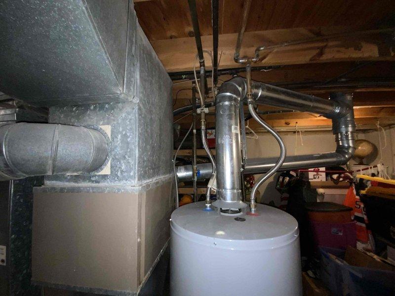 Provided estimate for complete HVAC system replacement including natural gas furnace and air conditioning unit located in basement. Existing air conditioning system non-operational at 41+ years old, while furnace remains functional at 15 years but recommended for replacement under promotional offering. Assessed existing ductwork configuration, water heater clearances, and available space for new equipment installation in unfinished basement area with concrete flooring.