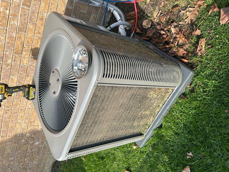 Completed annual cooling maintenance on residential outdoor condensing unit. Inspected condenser coil and noted moderate accumulation of dust and environmental debris causing discoloration. Evaluated circular fan assembly and verified operational integrity of motor hub and radial fin configuration. Assessed filter panel condition, observing dirt buildup and requiring replacement. Documented refrigerant line connections and PVC piping for proper installation. Unit housing showed normal weathering consistent with outdoor exposure but maintained structural integrity. Captured photographic documentation of equipment condition before service completion.