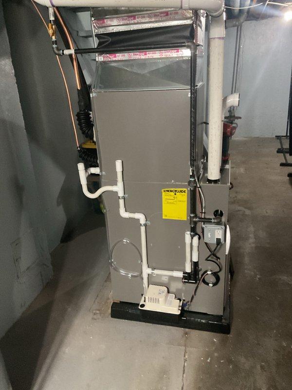 Completed full HVAC system installation including new furnace and air conditioning unit in basement utility area. Installed air handler with proper electrical connections, control box wiring, and mounted all components on secure platform with metal ductwork connections. Configured PVC condensate drainage system with multiple bends and proper routing, connected refrigerant lines with black flexible conduit, and ensured all manufacturer specifications were met per code requirements.