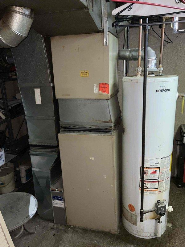 Provided comprehensive estimate for complete HVAC system replacement including both air conditioning and natural gas furnace under promotional offer. Evaluated 29-year-old existing equipment located in basement, with furnace currently non-operational while air conditioning unit still functioning. Documented existing beige cabinet-style furnace with connected ductwork and assessed installation conditions including concrete floor workspace, exposed ceiling joists, and existing ventilation infrastructure for replacement planning.
