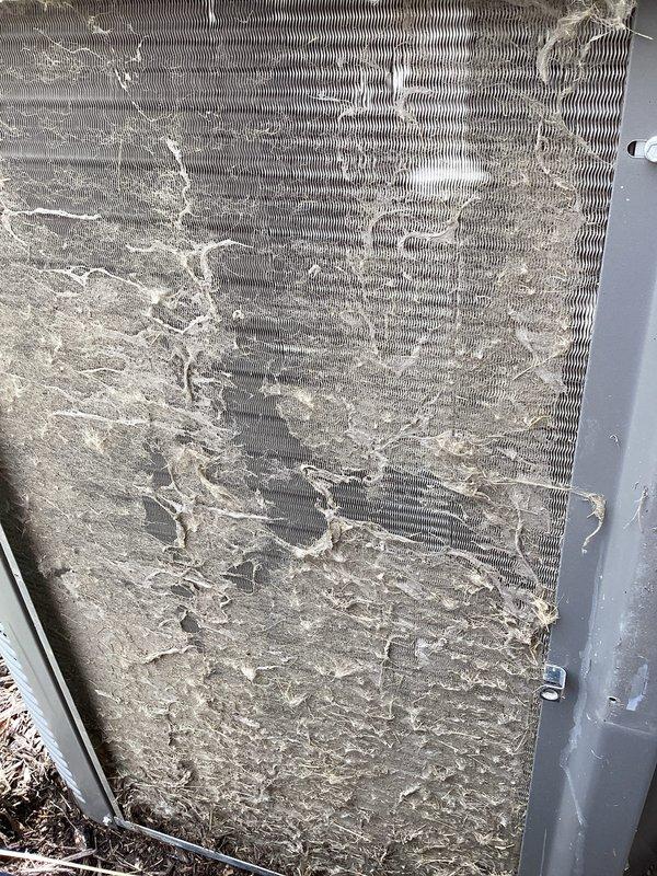 Performed annual cooling maintenance on outdoor condensing unit. Inspected condenser coils and found significant accumulation of dust, dirt, and debris throughout the fin assembly, restricting airflow and reducing heat transfer efficiency. Removed access panels and cleaned condenser coils to restore proper airflow. Verified unit operational status and documented pre-maintenance condition with photographs showing heavy contamination on heat exchanger surfaces.