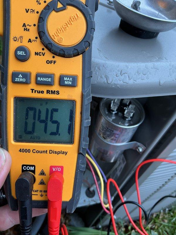 Responded to no cooling call on 2021 A/C system located in basement. Upon arrival, performed diagnostic testing using digital multimeter to check electrical components. Measured voltage and capacitance readings on the run capacitor, which displayed 74.5 microfarads on initial testing and 4.9 microfarads on secondary verification, indicating capacitor failure below manufacturer specifications. Replaced defective dual run capacitor with proper OEM replacement unit. Verified all electrical connections, tested compressor and condenser fan motor operation, and confirmed system returned to normal cooling operation. Unit tested successfully with proper amperage draw and voltage supply. Work completed under parts and labor warranty coverage.