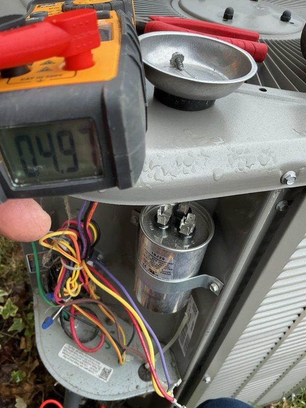 Responded to no cooling call on 2021 A/C system located in basement. Upon arrival, performed diagnostic testing using digital multimeter to check electrical components. Measured voltage and capacitance readings on the run capacitor, which displayed 74.5 microfarads on initial testing and 4.9 microfarads on secondary verification, indicating capacitor failure below manufacturer specifications. Replaced defective dual run capacitor with proper OEM replacement unit. Verified all electrical connections, tested compressor and condenser fan motor operation, and confirmed system returned to normal cooling operation. Unit tested successfully with proper amperage draw and voltage supply. Work completed under parts and labor warranty coverage.