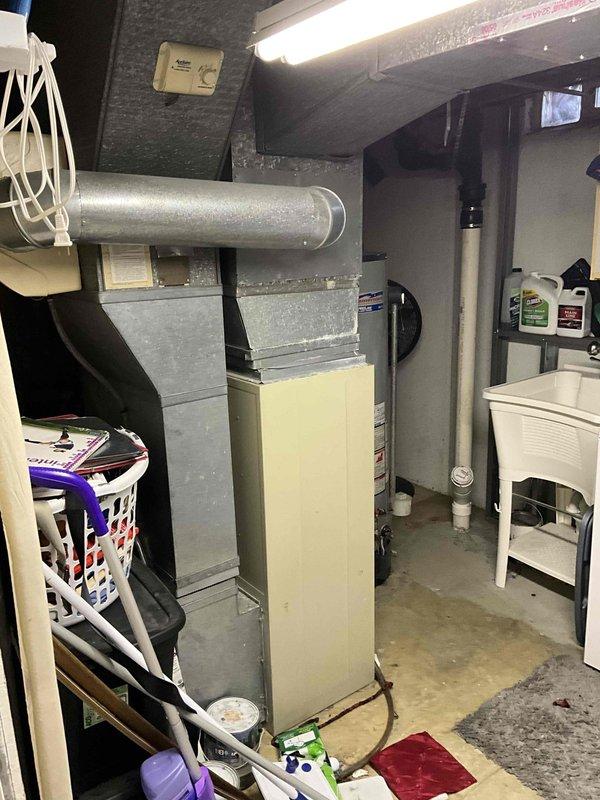 Provided estimate for complete furnace and air conditioning system replacement in basement location. Existing 1987 heating system is non-operational and has exceeded its serviceable lifespan. Assessed current installation including ductwork configuration, electrical service capacity at main panel, and available clearances in utility room shared with water heater and storage. Documented existing equipment layout and electrical infrastructure to determine proper sizing and installation requirements for new HVAC system.
