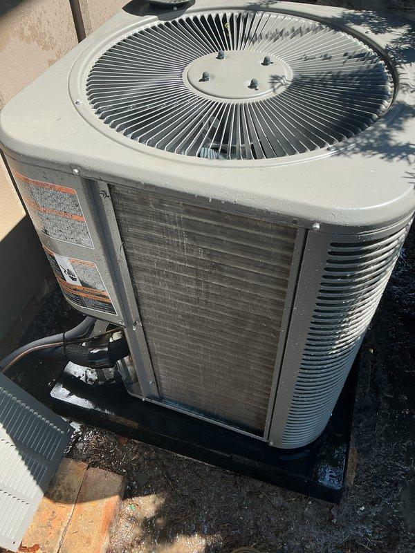 Completed annual cooling maintenance on outdoor condensing unit. Performed comprehensive system inspection including visual assessment of cabinet condition, coil cleanliness, and overall equipment operation. Unit showed significant exterior weathering with heavy black streaking and staining on metal panels, indicating accumulated dirt, oxidation, and biological growth. Documented equipment condition with detailed photographs for service records. Heat exchanger coils exhibited dust and debris buildup typical of outdoor HVAC equipment. Verified fan grille assembly and mounting hardware secure. System operational at time of service completion.
