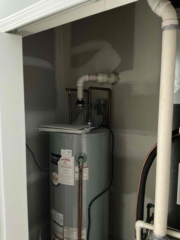 Conducted on-site assessment for water heater and water softener replacement in residential property. Evaluated existing water heater installation in utility closet, documenting current configuration with PVC and metal supply lines, gas connections, and electrical components. Inspected unfinished basement area with exposed framing and measured available space for new equipment installation, noting existing copper plumbing infrastructure and concrete floor preparation requirements. Photographed current installations and provided comprehensive estimate for replacement of both water heater and water softener systems.