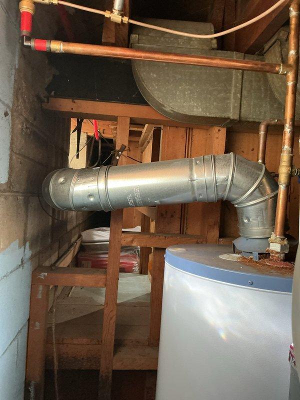 Responded to service call for failing water heater and furnace venting system in basement. Upon inspection, found improperly secured galvanized ductwork with compromised connections between appliances. Reinstalled and secured vertical B-vent piping with proper support brackets and sealed all joints to ensure safe exhaust ventilation. Verified proper draft and clearances on recently installed equipment dating to May 2024, confirming both furnace and water heater are now venting correctly with no signs of backdraft or separation.