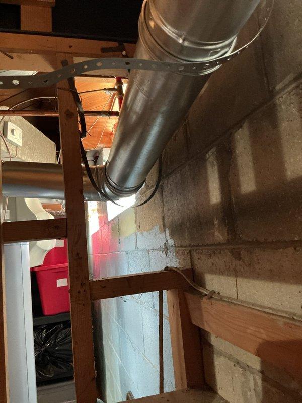 Responded to service call for failing water heater and furnace venting system in basement. Upon inspection, found improperly secured galvanized ductwork with compromised connections between appliances. Reinstalled and secured vertical B-vent piping with proper support brackets and sealed all joints to ensure safe exhaust ventilation. Verified proper draft and clearances on recently installed equipment dating to May 2024, confirming both furnace and water heater are now venting correctly with no signs of backdraft or separation.