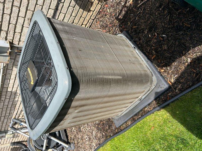 Completed annual cooling maintenance on residential outdoor condenser unit. Inspected unit exterior condition, verified proper placement on concrete pad, and documented heavy dirt and debris accumulation on top fan grille requiring attention. Unit operational with normal weathering consistent with outdoor installation.