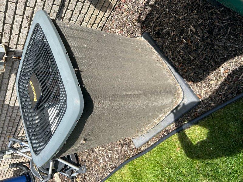 Completed annual cooling maintenance on residential outdoor condenser unit. Inspected unit exterior condition, verified proper placement on concrete pad, and documented heavy dirt and debris accumulation on top fan grille requiring attention. Unit operational with normal weathering consistent with outdoor installation.