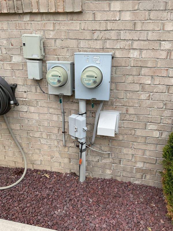 Conducted comprehensive site assessment for electrical panel upgrade at residential property. Documented existing dual-meter exterior installation mounted on brick exterior, including current service distribution equipment, conduit routing, and utility connections. Evaluated interior utility space accessibility and clearance requirements for potential panel installation, noting storage configuration and available working area. Photographed current electrical infrastructure to support upgrade specifications and permit documentation.