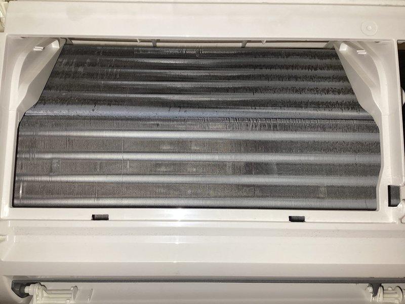 Responded to service call for 4-year-old mini split system reporting sweet smell from indoor unit after outdoor condenser was knocked over during windstorm. Upon inspection, unit was operational and maintaining cooling capacity with no visible refrigerant leaks at exterior condenser location. Opened indoor evaporator unit and found moderate dust and dirt accumulation on coil fins, with darker patches indicating restricted airflow contributing to odor issue. Documented internal coil condition with photos showing contaminated evaporator surfaces. System remained functional throughout inspection with no immediate safety concerns identified.