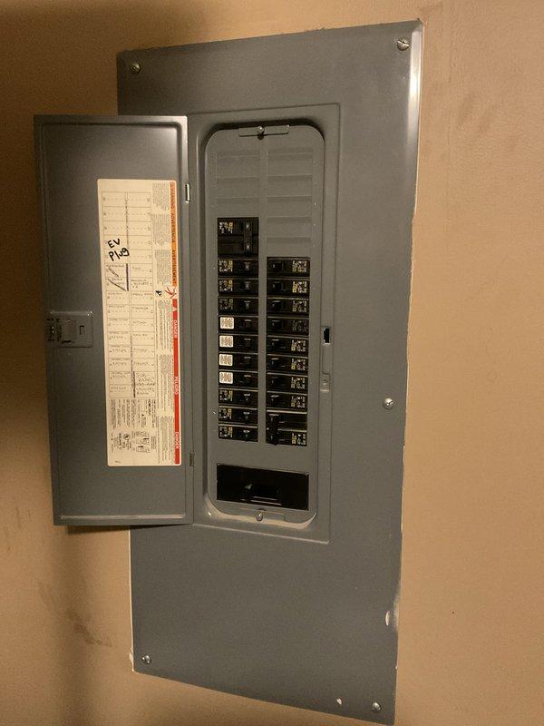 Installed a dedicated EV charger outlet on the exterior of the residence, running weatherproof conduit from a new circuit breaker in the main electrical panel to a gray NEMA outlet box mounted on the home's siding. Added and labeled a new breaker in the panel to support the charging station load, with proper circuit directory documentation noting "EV Plug" for future reference.