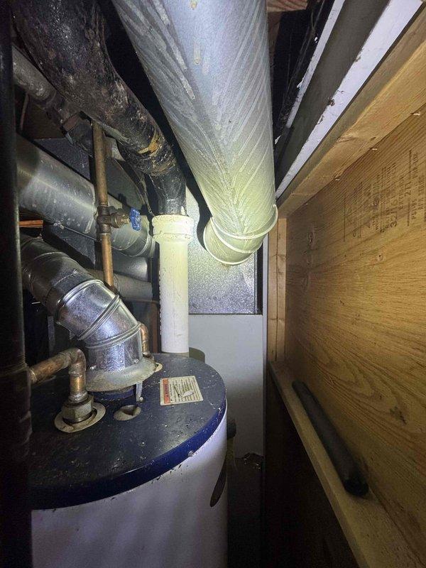Conducted comprehensive on-site assessment for complete HVAC system replacement in single-family residence under 800 square feet. Evaluated existing furnace and air conditioning equipment located in confined basement mechanical space, documenting current system configuration including ductwork routing, clearance constraints, and utility connections. Photographed installation area showing beige furnace unit with vertical exhaust venting, adjacent water heater with corroded piping, and silver metallic ductwork running through structural beams with limited clearance. Assessed mechanical room layout including plywood subflooring, electrical outlets, support columns, and tight workspace conditions that will impact equipment removal and new system installation. Prepared detailed estimate for expedited full system replacement including new furnace and air conditioning unit sized appropriately for square footage, accounting for existing ductwork integration and space limitations in mechanical 