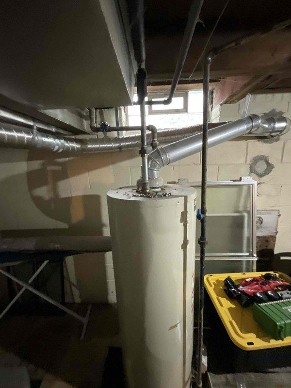 Provided estimate for new tankless water heater installation to replace existing non-functional 50-gallon standard natural draft unit in basement utility area. Assessed current plumbing configuration, venting requirements, and gas line capacity to determine specifications for tankless conversion. Documented existing Reliance water heater location, surrounding piping layout, and available space for proper tankless unit installation and code-compliant venting modifications.